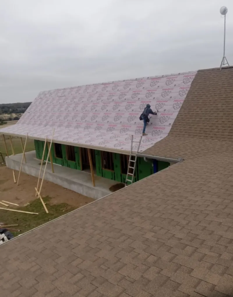 Worker preparing underlayment for a metal roof installation in Oak Park